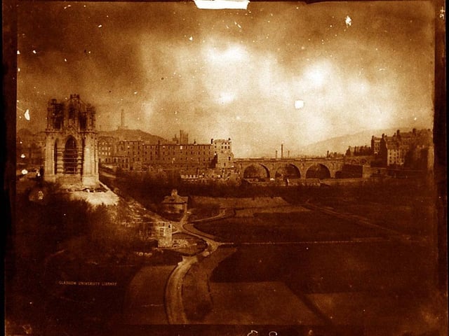 In this view from circa 1844, a half-finished Scott Monument rises from East Princes Street Gardens. The original North Bridge can be seen in the distance.